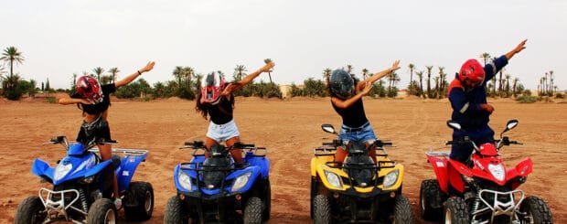 Group of riders exploring the Marrakech desert on quad bikes, kicking up dust with stunning Moroccan landscapes in the background.