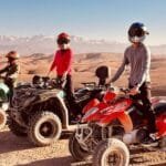 A rider on a quad bike speeding through the rocky terrain of the Agafay Desert with stunning desert landscapes in the background.