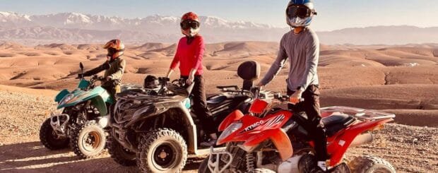 A rider on a quad bike speeding through the rocky terrain of the Agafay Desert with stunning desert landscapes in the background.