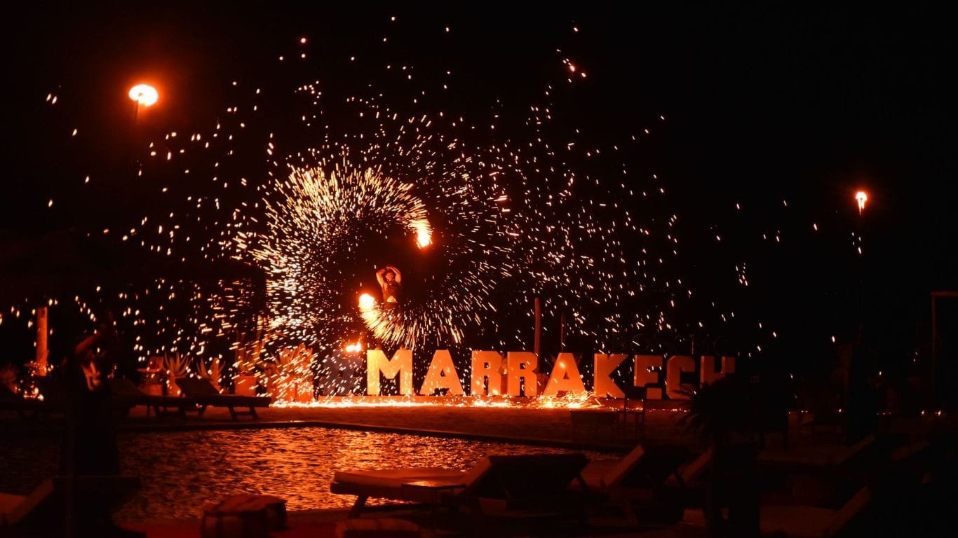 Traditional Moroccan entertainment with fire performers and musicians in the Agafay Desert at night.